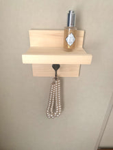 Accent shelf with ledge on wall holding skincare products and a pearl necklace
