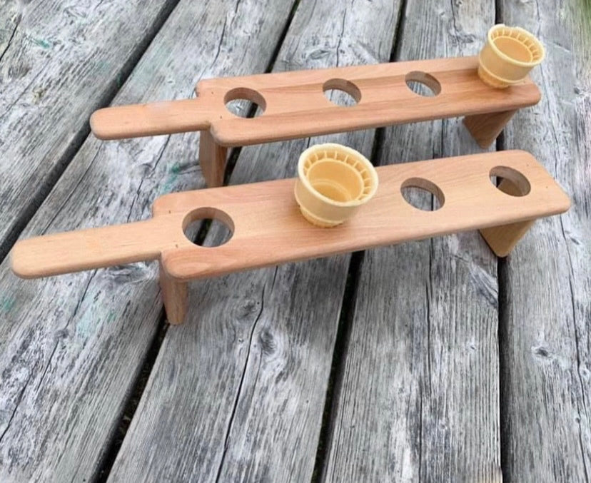 Handmade solid wood ice cream cone holder stand with handle on a weathered grey picnic table.