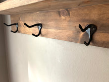Black double hooks on dark walnut wood foyer shelf