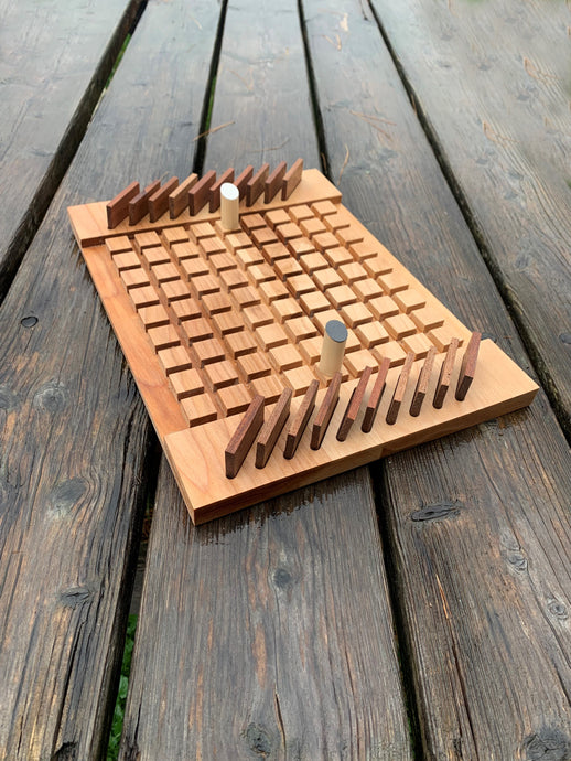 Wooden board game created with 81 playing sqaures on a wood picnic table with two pegs and wood pieces
