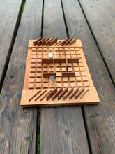 Wooden strategy and barricade,  logic-based board game on a picnic table with playing pieces in play.
